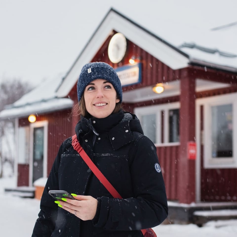 Rachel Schnalzer steht vor einem schneebedeckten Bahnhof